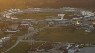 AX0163_0009 - 4K aerial stock footage of a reverse view of the Advanced Photon Source at the Argonne National Laboratory at sunset in Lemont, Illinois