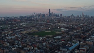 AX0163_0023 - 4K aerial stock footage of tilting from an urban West Side neighborhood to reveal the Chicago skyline at sunset, Illinois