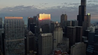 AX0163_0030 - 4K aerial stock footage of flying over a skyscraper reflecting the sunset, Downtown Chicago, Illinois