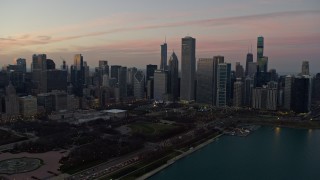 AX0163_0048 - 4K aerial stock footage approach skyscrapers bordering Grant Park at twilight, Downtown Chicago, Illinois