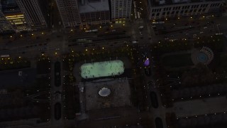 AX0163_0051 - 4K stock footage aerial video a bird's eye of the ice skating rink by the Cloud Gate in Grant Park at twilight, Downtown Chicago, Illinois