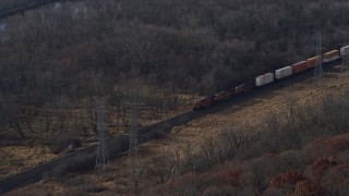 AX0165_0005 - 4K aerial stock footage of a reverse view of a train cruising past the countryside  in Lemont, Illinois