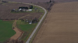 AX0166_0046 - 4K aerial stock footage of passing farmhouses by a country road in Bristol, Wisconsin