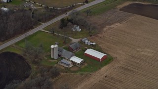 AX0166_0050 - 4K aerial stock footage of flying past a barn, silos and farmhouse in Bristol, Wisconsin