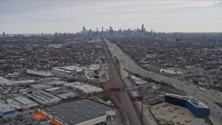 AX0167_0078 - 4K aerial stock footage of following light freeway traffic, tilt to reveal wide view of Downtown Chicago skyline, Illinois
