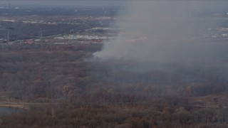 AX0168_0020 - 4K aerial stock footage of smoke rising from a fire in the woods, Willow Springs, Illinois