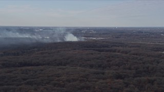 AX0168_0021 - 4K aerial stock footage of smoke rising from a fire in the forest, Willow Springs, Illinois