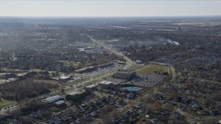 AX0168_0028 - 4K aerial stock footage of a strip mall and upscale homes near 19th Street, smoke rising from trees, in Lockport, Illinois