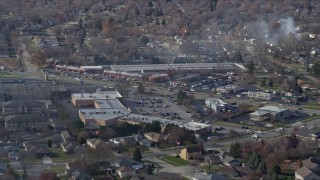AX0168_0029 - 4K aerial stock footage of shops on 19th Street, smoke rising from trees, in Lockport, Illinois