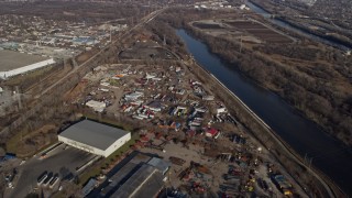 AX0169_0014 - 4K aerial stock footage of flying over warehouse buildings and a junkyard beside Des Plaines River, McCook, Illinois