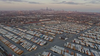 AX0170_0004 - 4K aerial stock footage tilt from train yard in Southwest Side to reveal distant Downtown Chicago skyline at sunset, Illinois
