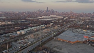 AX0170_0005 - 4K aerial stock footage tilt from warehouses and urban homes in Southwest Side to reveal distant Downtown Chicago skyline at sunset, Illinois
