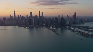 AX0170_0016 - 4K aerial stock footage reverse view of the Downtown Chicago skyline at sunset, reveal Navy Pier, Illinois