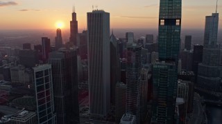 AX0170_0018 - 4K stock footage aerial video of flying by Downtown Chicago skyscrapers with a view of the setting sun, Illinois