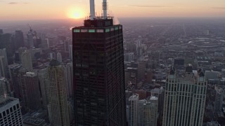 AX0170_0020 - 4K aerial stock footage of flying around John Hancock Center to reveal the setting sun, Downtown Chicago, Illinois