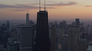 AX0170_0021 - 4K aerial stock footage of flying away from John Hancock Center, tilt to reveal Lake Shore Drive at sunset, Downtown Chicago, Illinois