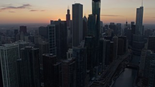 AX0170_0024 - 4K aerial stock footage focus on the setting sun while flying by skyscrapers in Downtown Chicago, Illinois