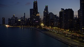 AX0170_0062 - 4K aerial stock footage approach Palmolive Building and Michigan Avenue from Lake Michigan at twilight, Downtown Chicago, Illinois
