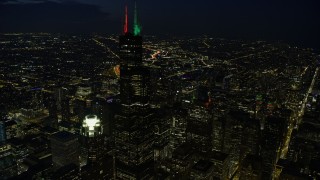 AX0170_0070 - 4K aerial stock footage of flying by Willis Tower with holiday lights at night, Downtown Chicago, Illinois