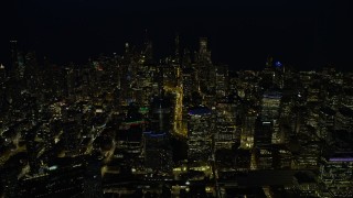 AX0170_0074 - 4K aerial stock footage of approaching downtown skyscrapers, some with holiday lights at night, Downtown Chicago, Illinois
