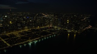 AX0170_0079 - 4K stock footage aerial video of approaching Grant Park and downtown skyscrapers, some with holiday lights at night, Downtown Chicago, Illinois