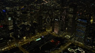 AX0170_0080 - 4K aerial stock footage fly over Grant Park nearby skyscrapers, some with holiday lights at night, Downtown Chicago, Illinois