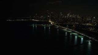 AX0170_0090 - 4K aerial stock footage of the city's skyline seen from near North Avenue Beach at night, Downtown Chicago, Illinois