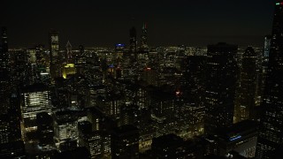 AX0170_0093 - 4K aerial stock footage tilt from the lake and ascend over downtown skyscrapers at night, Downtown Chicago, Illinois