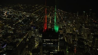 AX0170_0098 - 4K aerial stock footage approach the top of Willis Tower with holiday lights at night, tilt to bird's eye view, Downtown Chicago, Illinois