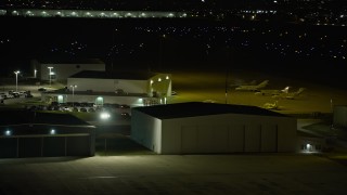 AX0170_0134 - 4K aerial stock footage of jets parked near hangars at Lewis University Airport at night, Romeoville, Illinois