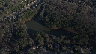AX0171_0132 - 6.7K aerial stock footage of tilt to a small lake by suburban homes in Lawrenceville, Georgia
