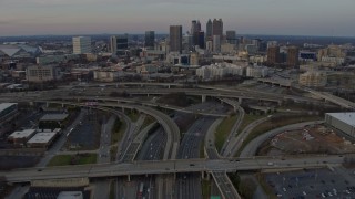 AX0171_0159 - 6.7K stock footage aerial video tilt from freeway interchange to reveal Downtown Atlanta skyline at sunset, Georgia
