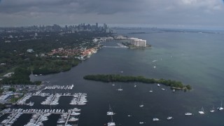 AX0172_014 - 6.7K stock footage aerial video tilting from boats in the water to reveal distant skyline of Downtown Miami, Florida