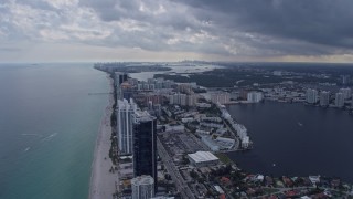 AX0172_073 - 6.7K aerial stock footage tilt from the ocean to reveal condo complexes in Sunny Isles Beach, Florida and distant Miami skyline