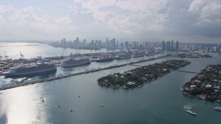 AX0172_126 - 6.7K stock footage aerial video of flying by islands and cruise ships at the port with view of the downtown skyline in Miami, Florida