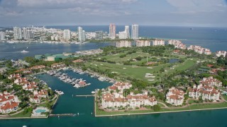 AX0172_129 - 6.7K stock footage aerial video ascend by Fisher Island oceanfront condo complexes, reveal golf course, Miami, Florida