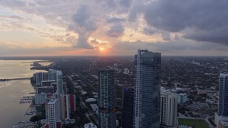 AX0172_169 - 6.7K aerial stock footage focus on setting sun while flying by Downtown Miami skyscrapers, Florida at sunset