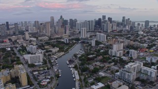 AX0172_182 - 6.7K aerial stock footage tilt from river to reveal and approach downtown skyscrapers at sunset, Miami, Florida