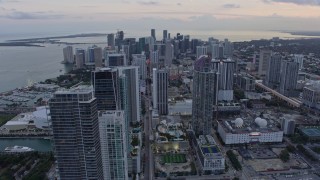 AX0172_184 - 6.7K stock footage aerial video tilt from Downtown Miami streets to reveal and approach skyscrapers at sunset, Miami, Florida