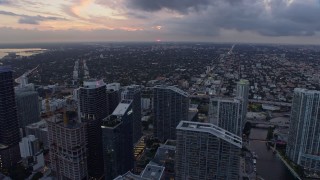 AX0172_189 - 6.7K stock footage aerial video fly over river and skyscrapers to approach the setting sun in Downtown Miami, Miami, Florida