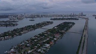 AX0172_193 - 6.7K stock footage aerial video fly over mansions on islands to approach Miami Beach at sunset, Miami, Florida