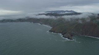 AX0173_0098 - 6K aerial stock footage of approaching fog-wreathed coastal cliffs, Marin Headlands, California