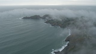 AX0173_0099 - 6K aerial stock footage of flying by wisps of fog over coastal cliffs, Marin Headlands, California