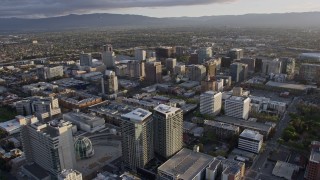 AX0174_0027 - 6K aerial stock footage of flying by office and apartment buildings in Downtown San Jose at sunset, California