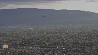 AX0174_0030 - 6K stock footage aerial video of a commercial airplane flying over San Jose at sunset, California