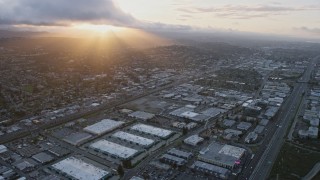 AX0174_0057 - 6K aerial stock footage of flying over warehouse buildings toward homes on a hill at sunset, San Carlos, California