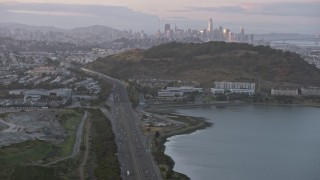 AX0174_0072 - 6K aerial stock footage tilt from freeway to reveal the distant San Francisco skyline at sunset, California