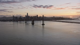 AX0174_0090 - 6K aerial stock footage of flying beside the Bay Bridge toward the Downtown San Francisco skyline at sunset, California