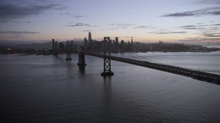 AX0174_0115 - 6K aerial stock footage of following the Bay Bridge toward the Downtown San Francisco skyline at twilight, California