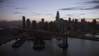 AX0174_0116 - 6K stock footage aerial video flyby the Bay Bridge with view of the Downtown San Francisco skyline at twilight, California